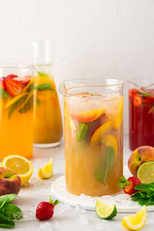 Jugs of fresh refreshing fruit drinks with fruit wedges, summer cold juices with iceの写真素材