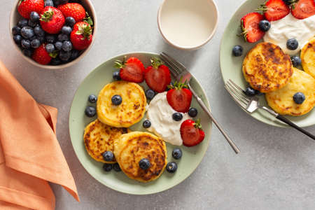 Cottage Cheese Pancake with strawberries, blueberries and sour cream, mug with milk and fresh berries, delicious breakfast, top viewの写真素材