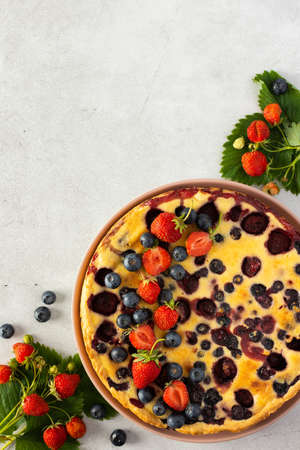 Strawberry blueberry pie decorated with fresh berries on a gray background, top viewの写真素材