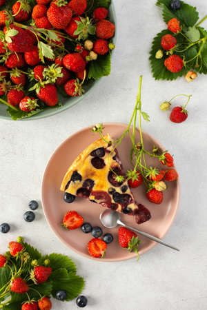 Piece of strawberry blueberry pie with fresh berries in a pink plate on a gray background, top viewの写真素材