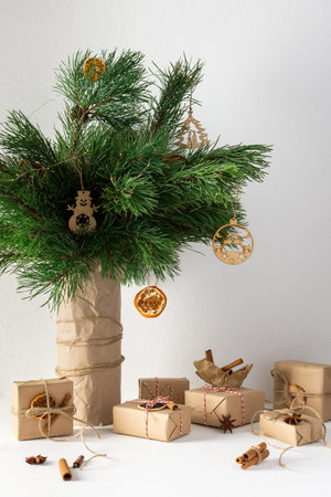 Festive christmas table, vase with pine branches and toys, gift boxes and dried citrus fruits,...