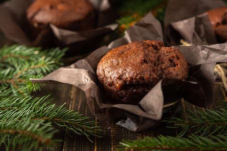 Delicious chocolate muffins on dark wooden background among fir branches, Merry Christmas and Happy New Yearの写真素材