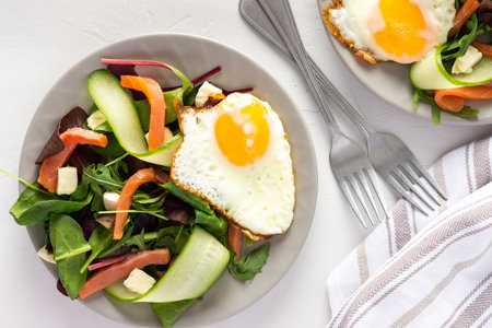 Fresh organic mesclun mix salad with cucumber, mozzarella and salmon, scrambled eggs, delicious hearty breakfastの写真素材