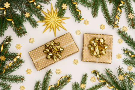 Festive background with gold decoration , green spruce branches and shiny golden serpentine confetti, golden gift boxes with bow ,glittering snowflakes , flat lay, top viewの写真素材