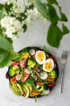 Delicious light breakfast, salad with tomatoes and radishes, avocado and boiled eggs, top viewの写真素材