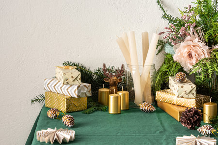 Festive decorated Christmas and New Years table, fir branches and decorative flowers, candles and golden gift boxes, Christmas tree decorations pine cones, deer and paper decorationsの写真素材