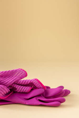 Pink microfiber cloth for washing and rubber gloves on a neutral beige background, cleaning conceptの写真素材