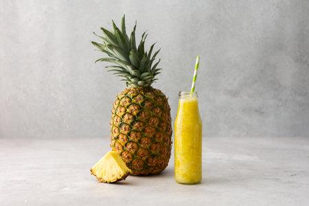 Whole and a slice of ripe delicious pineapple fruit and pineapple smoothie in a jar with a straw, copy spaceの写真素材