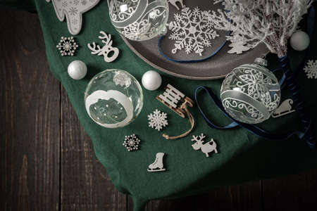 Christmas composition in white and green shades, christmas balls and candle, fir-tree and decorative fir-tree, christmas decoration and snowflakes on a green tablecloth, top view, copy spaceの写真素材