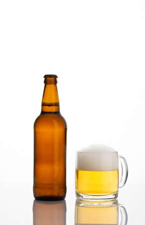 Brown full bottle of beer and glass with beer and foam isolated on white backgroundの写真素材