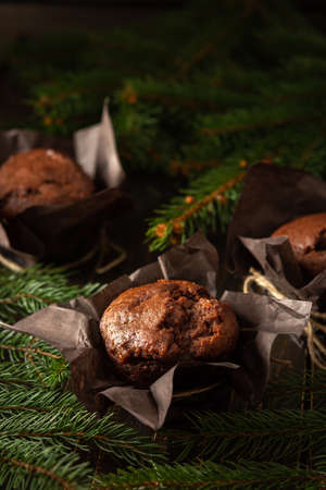 Delicious chocolate muffins on dark wooden background among fir branches, Merry Christmas and Happy New Yearの写真素材