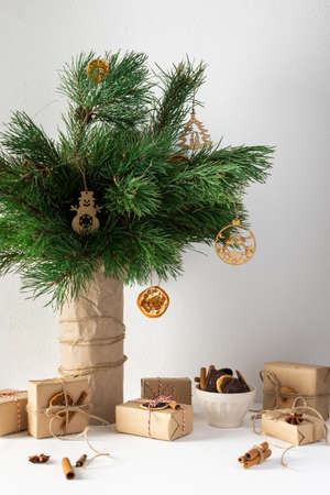 Festive christmas table, vase with pine branches and toys, gift boxes and a plate of chocolate cookies, dried citrus fruits, cinnamon with star aniseの写真素材