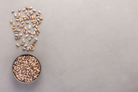 Legumes in bowl and scattered in the background, Pinto beans in a plate on a gray background, top view, copy spaceの写真素材