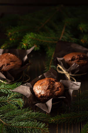 Delicious chocolate muffins on dark wooden background among fir branches, Merry Christmas and Happy New Yearの写真素材