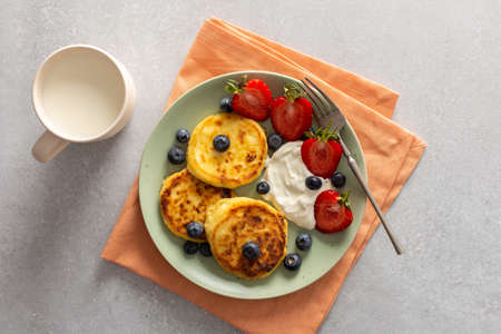 Cottage Cheese Pancake with strawberries, blueberries and sour cream, mug with milk , delicious breakfast, top viewの写真素材