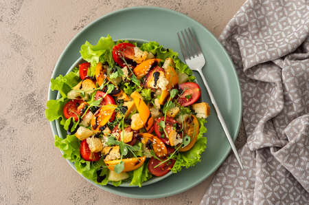 Light summer fresh salad with colorful tomatoes and croutons, lettuce and pineapple, sesame seeds and balsamic sauceの写真素材