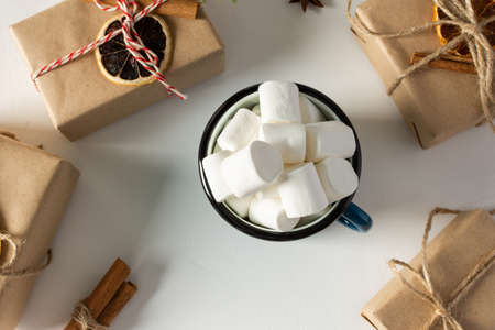 Festive christmas table top view, mug with marshmallows close up, gift boxes and dried citrus fruits, cinnamon with star aniseの写真素材