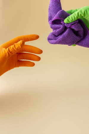 Hand in multi-colored rubber gloves holding a microfiber cloth for washing, cleaning conceptの写真素材