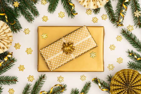 Festive background with gold decoration , green spruce branches and paper christmas tree decorations, golden gift boxes with bow ,glittering snowflakes , flat lay, top viewの写真素材