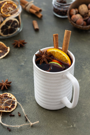 Mulled wine with lime and orange wedges, cinnamon and cloves, hot winter drink in a mugの写真素材