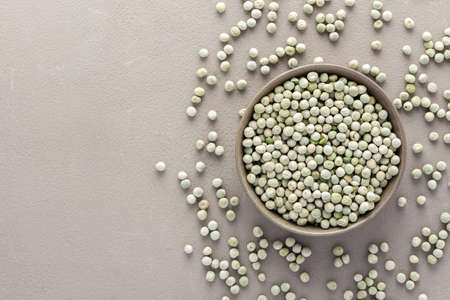 Legumes in bowl and scattered in the background, green peas in a plate on a gray background, top view, copy spaceの写真素材