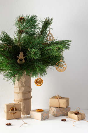 Festive christmas table, vase with pine branches and toys, gift boxes and dried citrus fruits with star aniseの写真素材