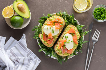 Delicious hearty breakfast, sandwiches with avocado paste, salmon and mozzarella on a plate with arugula and pea sproutsの写真素材
