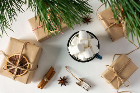 Festive christmas table top view, pine branches and mug with marshmallows, gift boxes and dried citrus fruits, cinnamon with star aniseの写真素材