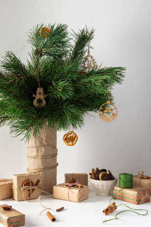 Festive christmas table, vase with pine branches and toys, gift boxes and a plate of chocolate cookies, dried citrus fruits, cinnamon with star aniseの写真素材