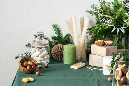 Festive decorated Christmas or New Year's table, thuja and spruce branches, candles and cookies in a jar , gift boxes and paper decorations, hazelnuts in coconut shellsの写真素材
