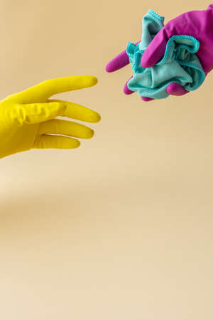 Hand in multi-colored rubber gloves holding a microfiber cloth for washing, cleaning conceptの写真素材