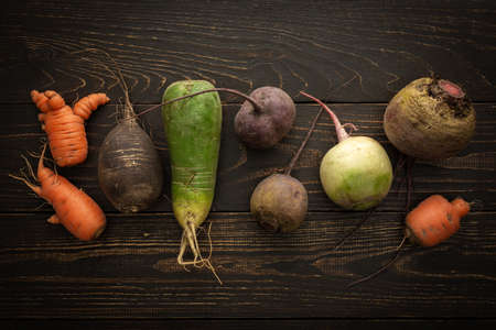 Root vegetables on a wooden background, different types of radish with beetroot and carrots, organic farm vegetablesの写真素材