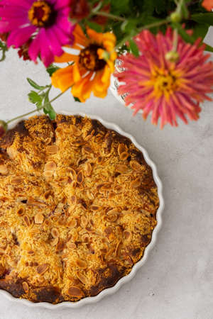 Homemade plum cake with almond flakes, autumn flowers in a vaseの写真素材