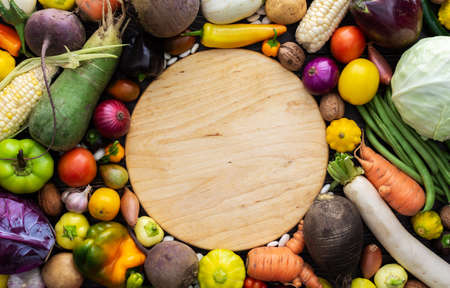 Background with fresh autumn vegetables, cutting board in the middle of the background, organic healthy farm products, top viewの写真素材