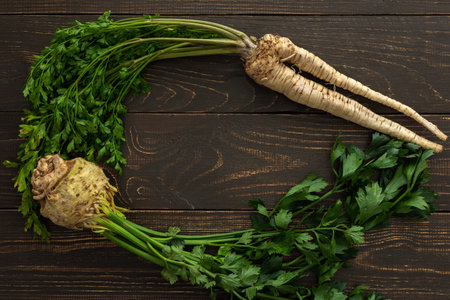 Root vegetables with green leaves on a wooden background, parsley root and celera, farm vegetables