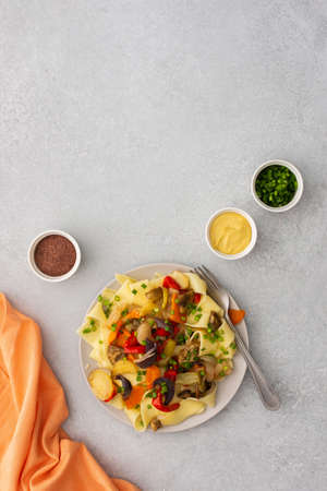 Fettuccine pasta with stewed vegetables, delicious autumn lunch in plate with mustard and fresh green onionsの写真素材