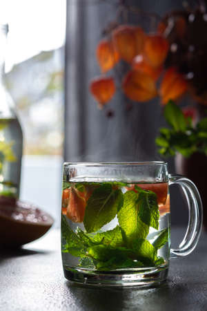 Healthy hot drink with mint and grapefruit in glasses, steam rises, aromatic mint tea with citrus fruitsの写真素材