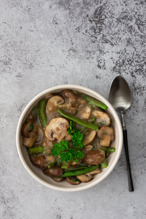 Fried brown champignons mushrooms with green beans in a creamy sauce with green onions and parsley, top viewの写真素材