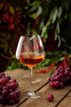 Autumn cozy romantic evening outdoors, wooden table with a glass of rose wine and grapesの写真素材