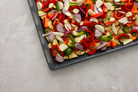 Fresh assorted autumn cut vegetables on a baking sheet ready to roast in the ovenの写真素材
