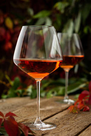 Autumn cozy romantic evening outdoors, wooden table with glasses with rose wine and grapesの写真素材