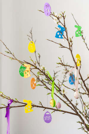 Blooming cherry branches decorated with colorful ribbons with easter eggs, decorative rabbits, happy easter, holiday decorationの写真素材