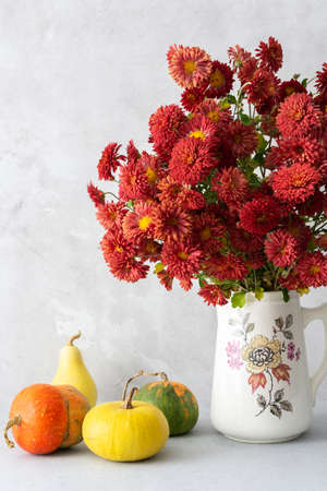 Beautiful bouquet of autumn chrysanthemum flowers in a vase and various colorful pumpkins on the table, Thanksgiving holiday, autumn home decorationの写真素材