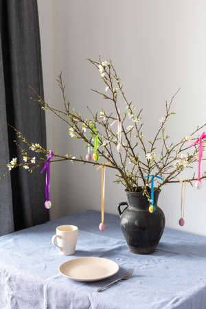Blooming cherry branches decorated with colorful ribbons with easter eggs, Happy Easter, table settingの写真素材