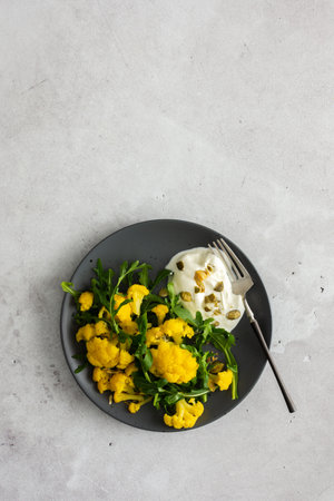 Salad with yellow cauliflower and arugula, Greek yogurt and pumpkin seeds, a light healthy breakfast, top viewの写真素材