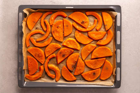 Chopped baked sweet butternut pumpkin on a baking sheet, top viewの写真素材