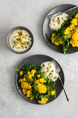 Salad with yellow cauliflower and arugula, Greek yogurt and pumpkin seeds, a light healthy breakfast, top viewの写真素材