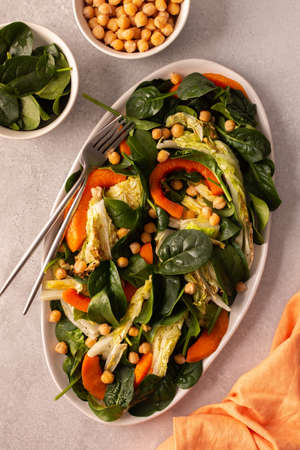 Healthy delicious vegetarian salad of spinach and chickpeas, baked pumpkin and Chinese cabbage, top view of an oval dish with saladの写真素材