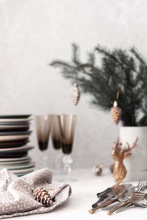 Preparing for a festive table setting, a stack of different plates and forks with knives, fir branches in a concrete vase, Christmas decorationsの写真素材