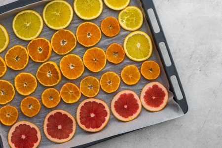 Sliced orange, tangerine and grapefruit slices on baking sheet, preparing citrus wedges for Christmas garlandの写真素材